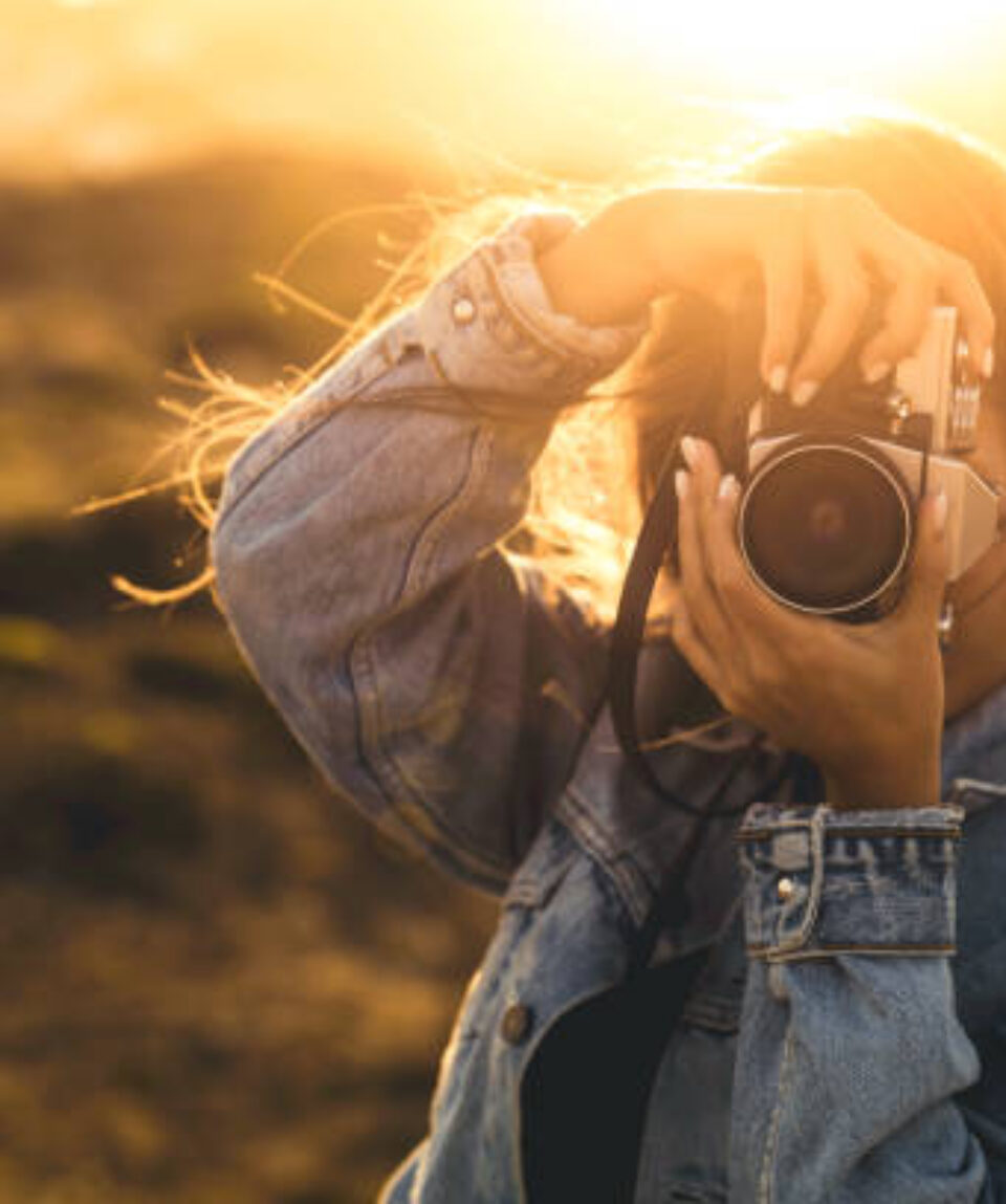 Beautiful woman taking picture outdoors with a analog camera